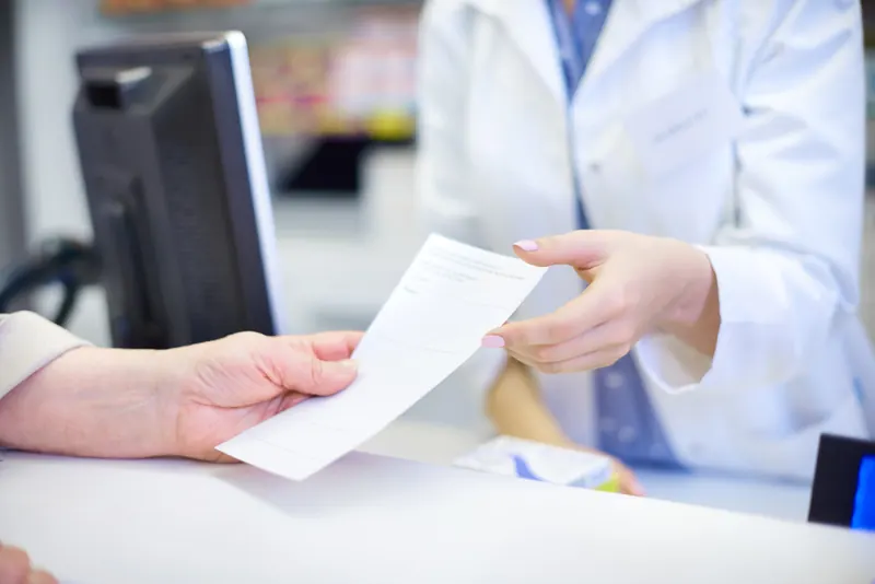 Entrega de una fórmula médica en el mostrador de una farmacia